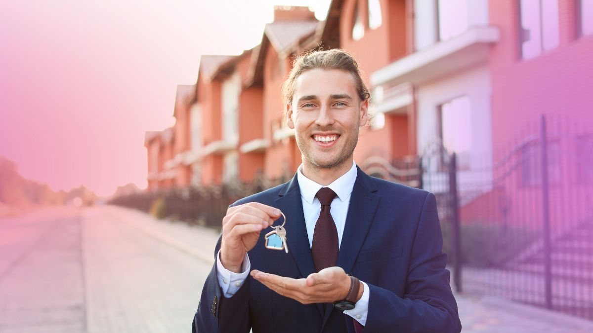 A real estate agent holding house keys in front of a row of townhouses