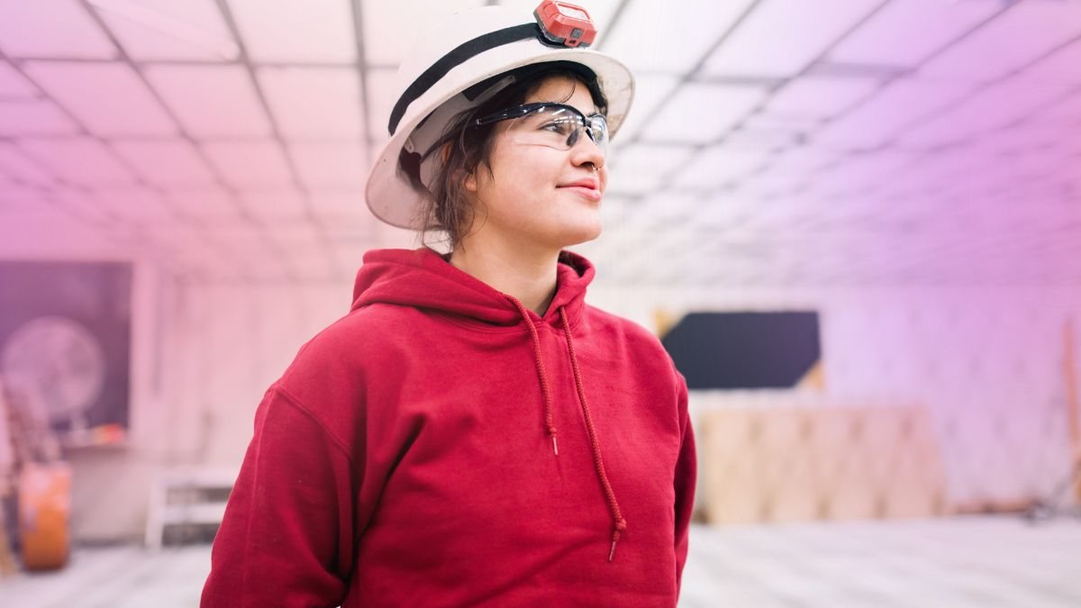 A tradesperson in a hard hat and safety glasses on site