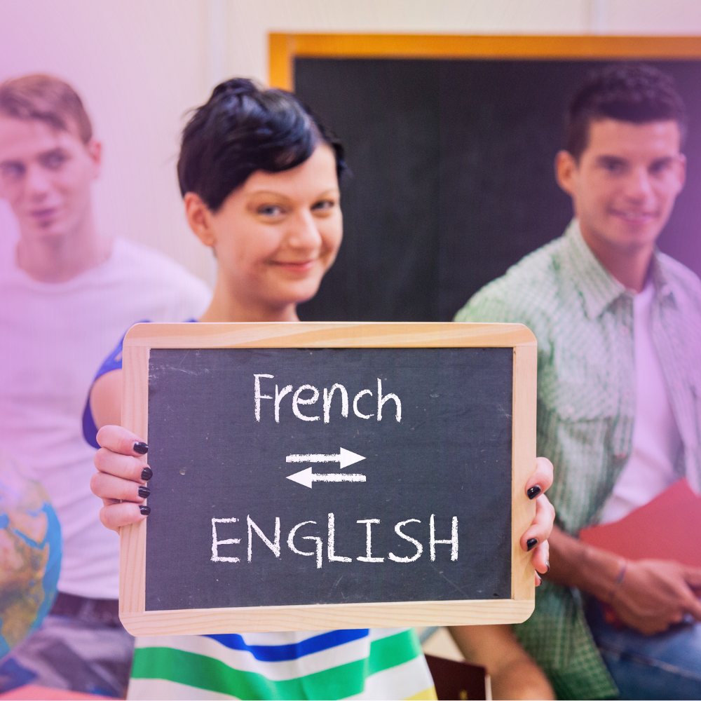 A woman holding a chalkboard reading French and English with arrows between them